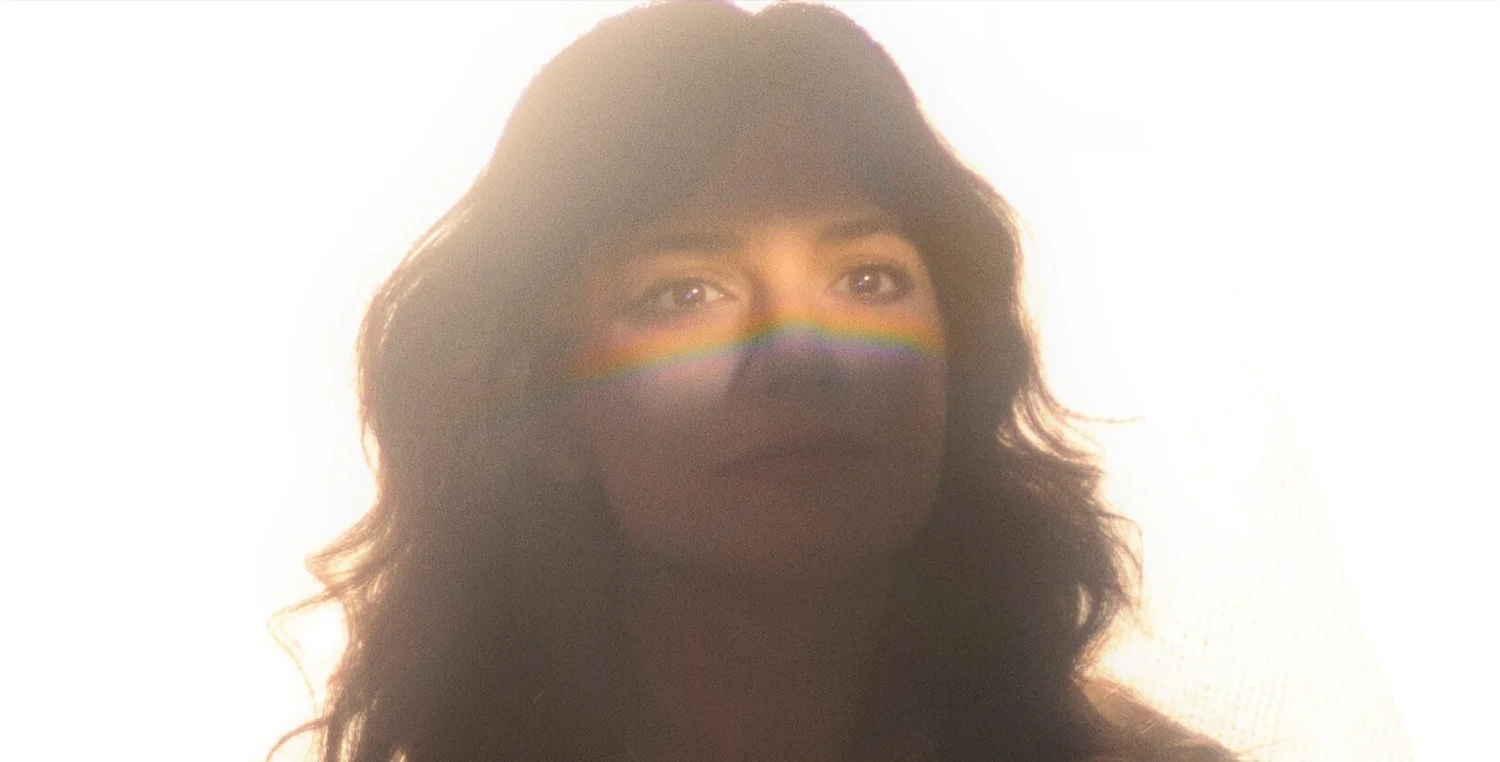 Thayer Sarrano press photo artist in shadow with reflected light from a prism in her eyes